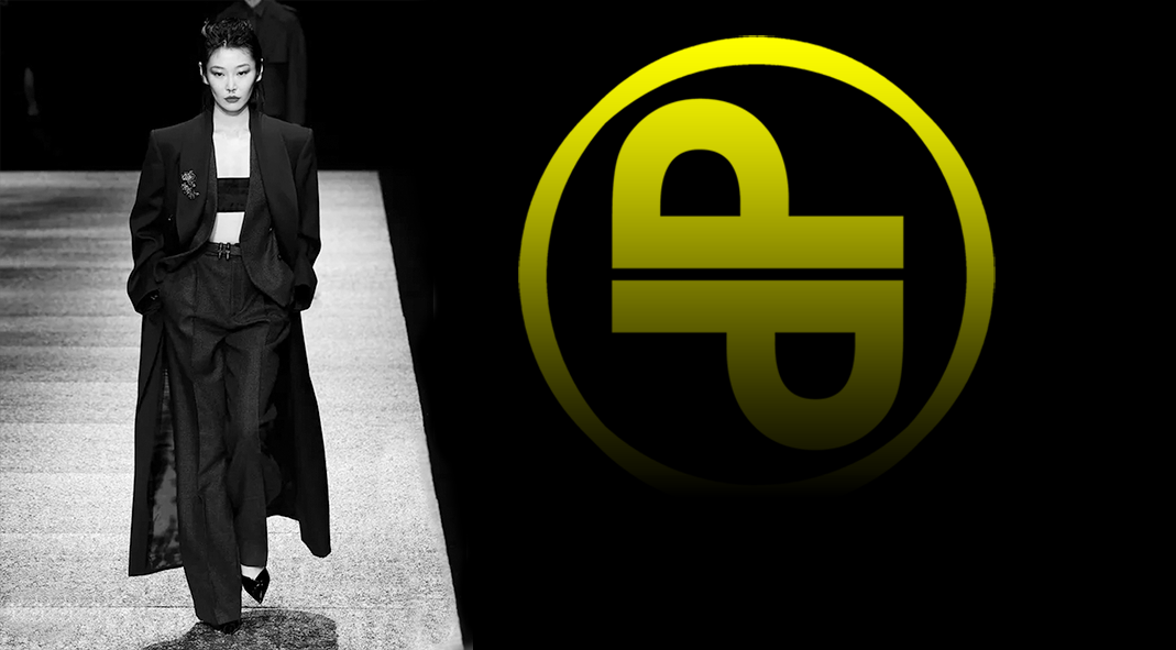 a model walking a runway in a black tailored suit, beside the perluca management monogram.
